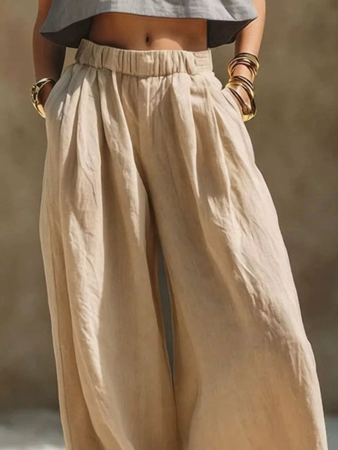 Sand pleated palazzo pants close-up with hands in the pockets
