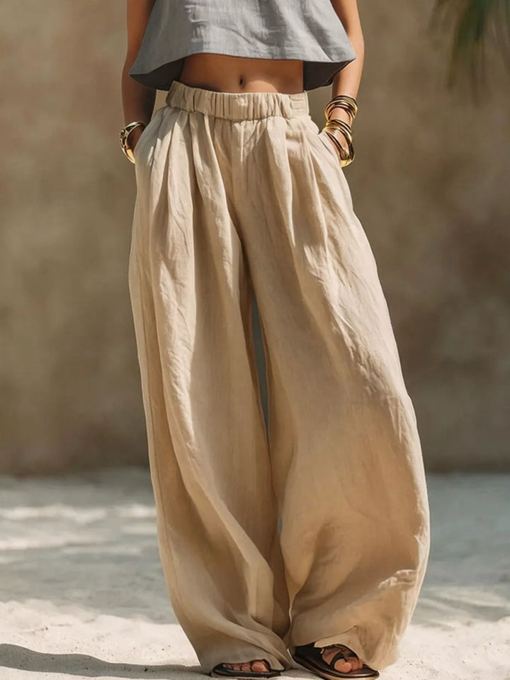 Sand palazzo pants with pleats and an elastic waist, worn with a gray top