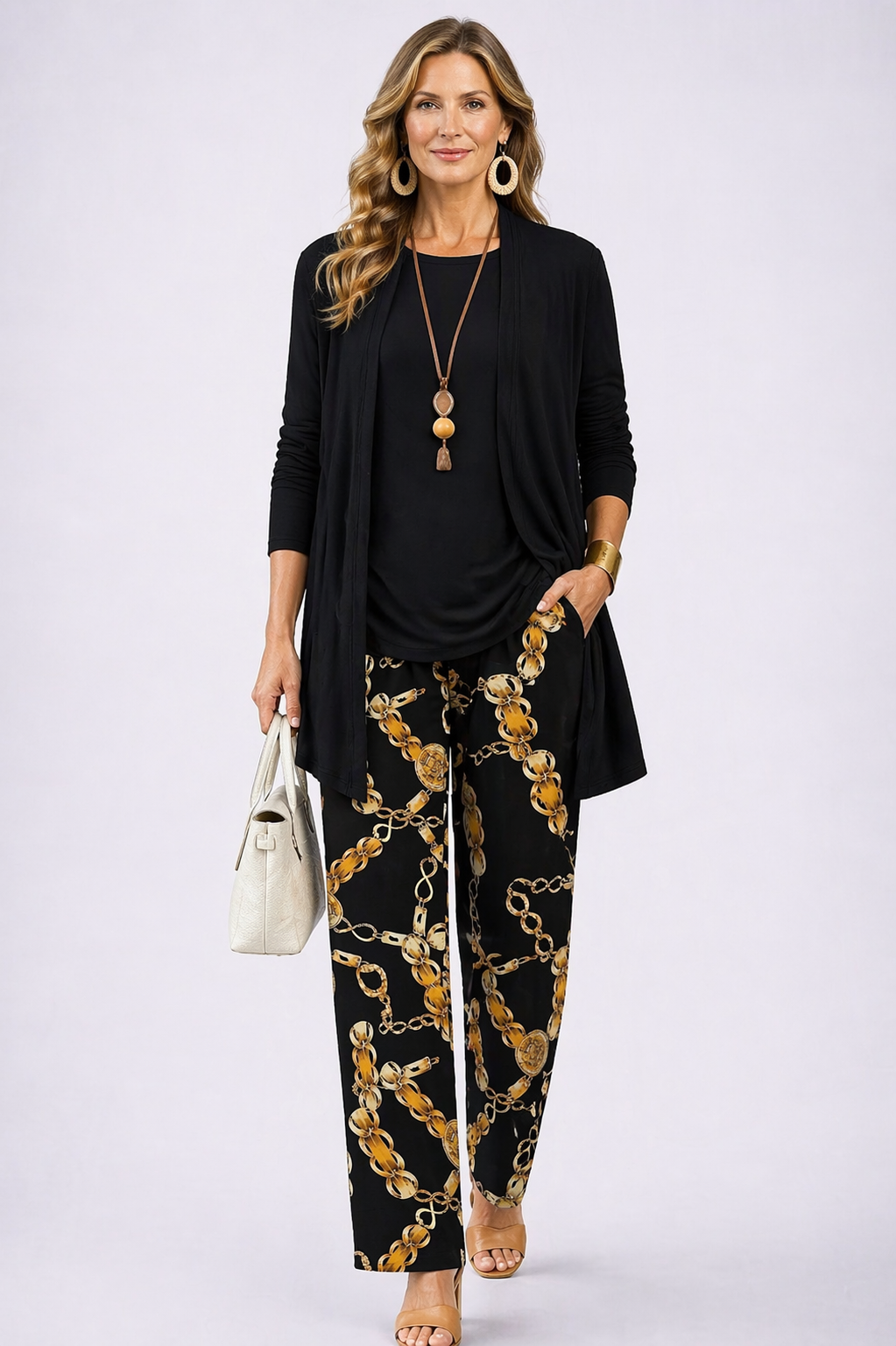 Women's pant suit in black with a draped open cardigan, black top and gold chain print pants