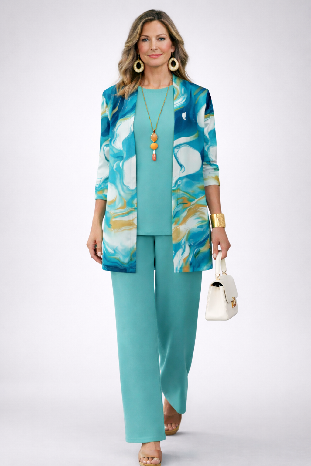Front view of the blue, white and gold wave print cardigan over the turquoise top