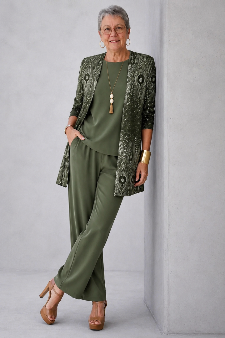 Olive ogee print cardigan worn with hands in the pant pockets, leaning on a wall