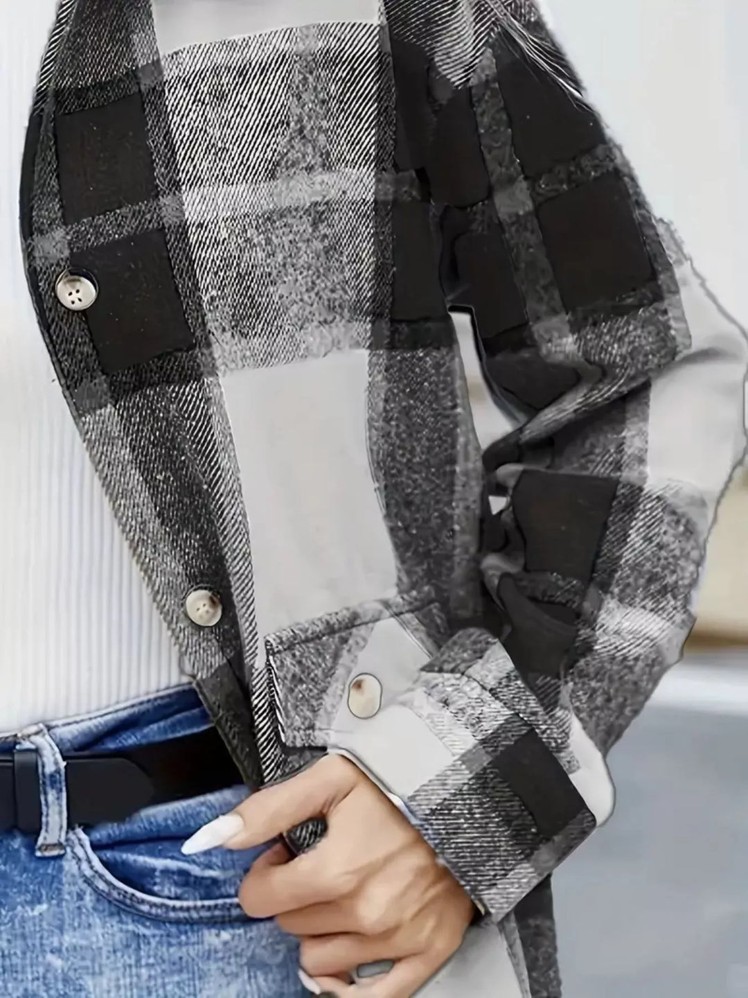 Close-up of the black plaid shacket pocket flap and buttoned sleeve cuff