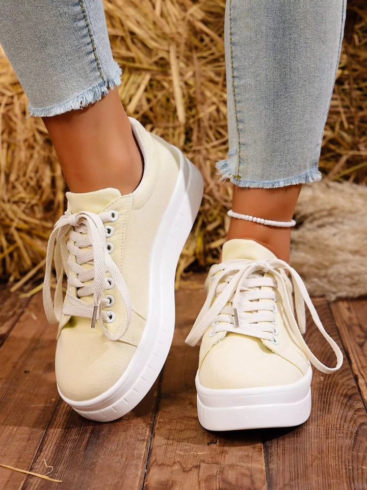 Cream platform sneakers with chunky white sole, laces loosely tied, front view