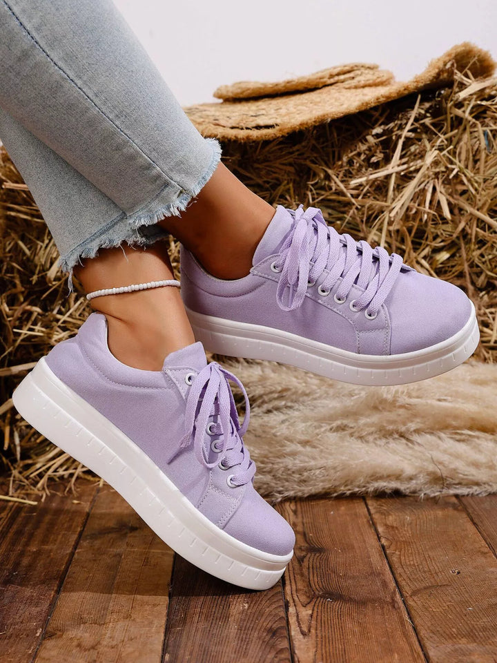 Lilac platform sneakers with thick white sole, side angle on wood planks