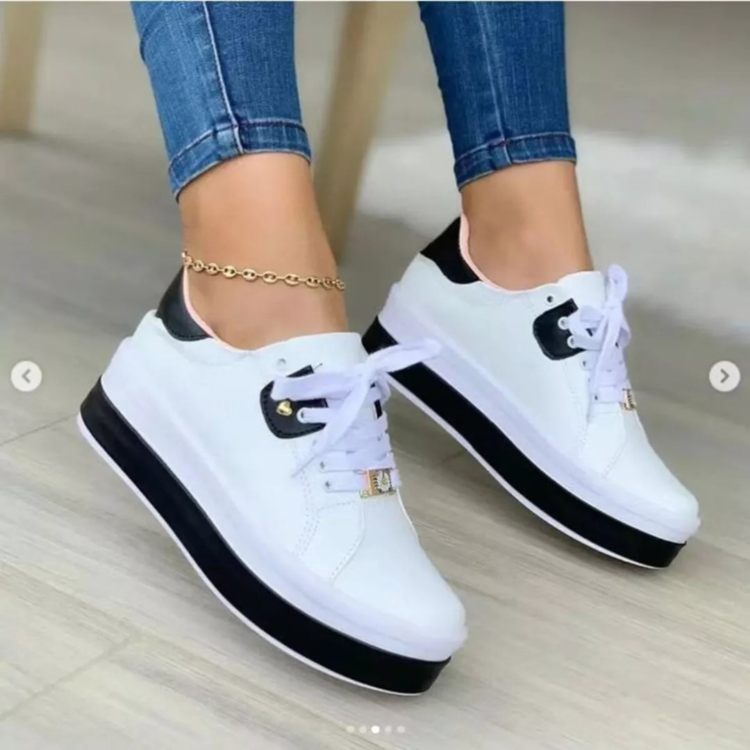 Women's platform sneakers in white and black with chunky two tone sole, worn with jeans
