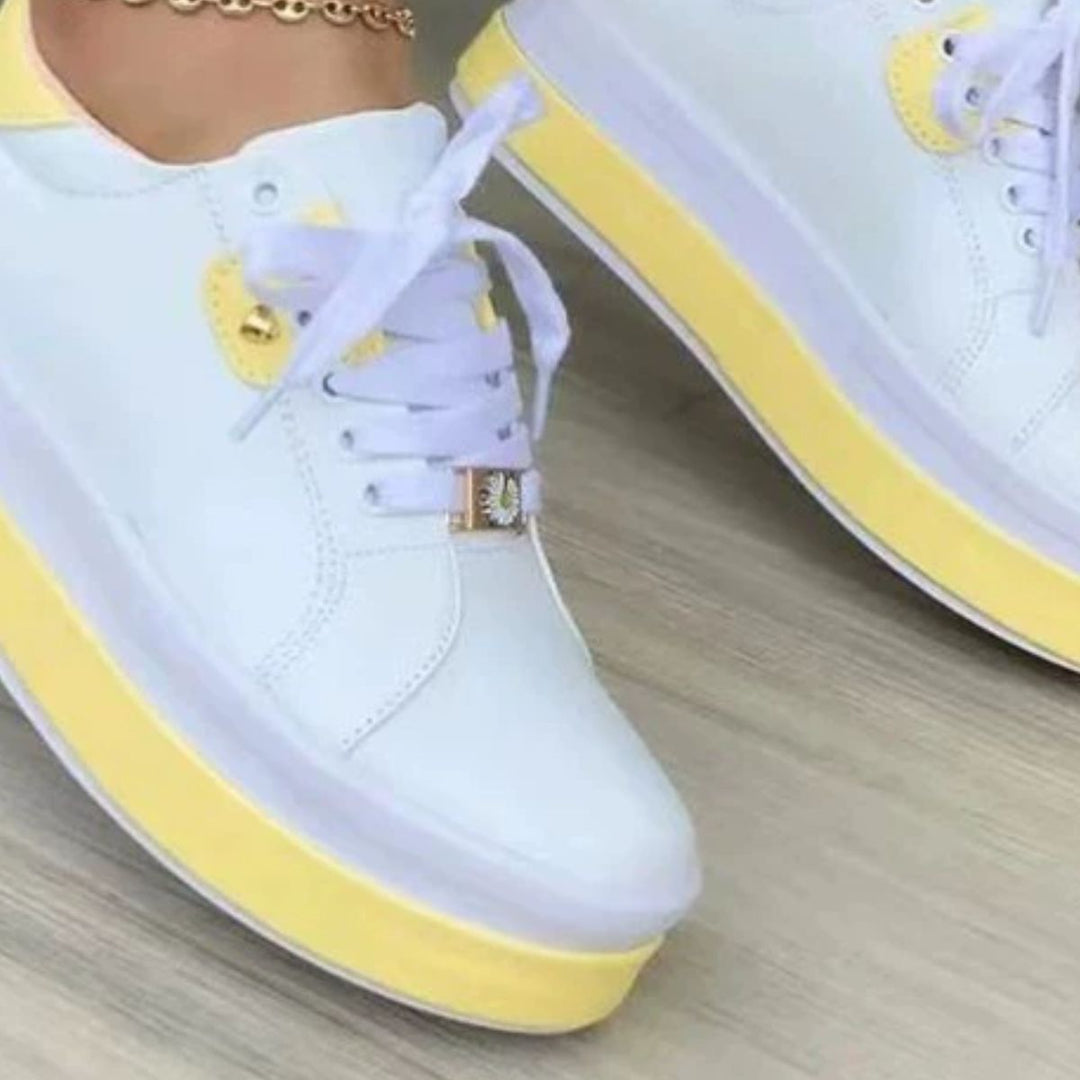 Close-up of white sneaker with yellow two tone platform sole and charm