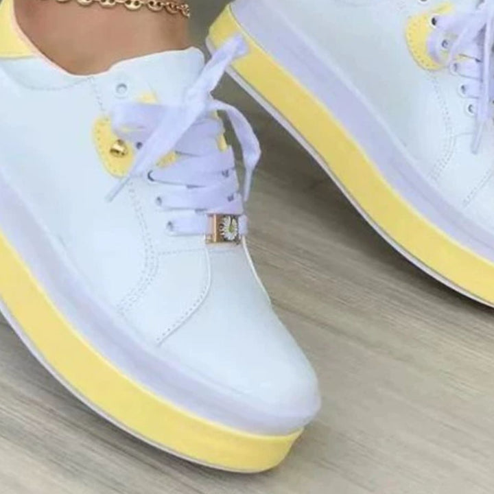 Close-up of white sneaker with yellow two tone platform sole and charm