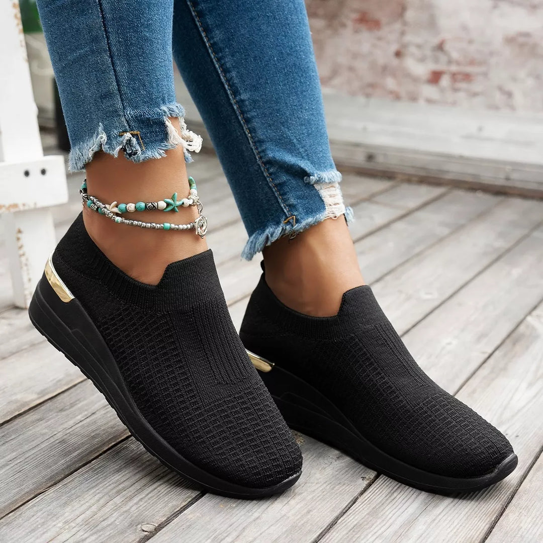 Women's platform sneakers in black slip on knit worn with cuffed jeans