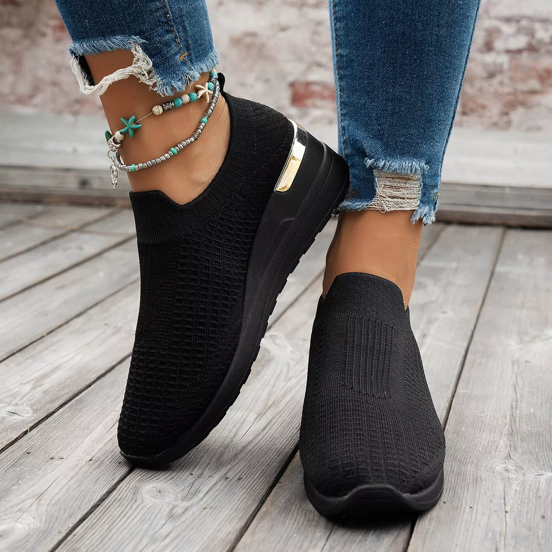 Pair of black slip on platform sneakers with hidden wedge and gold accent