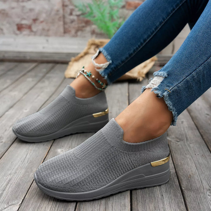 Side view of gray knit platform sneakers with hidden wedge and gold detail