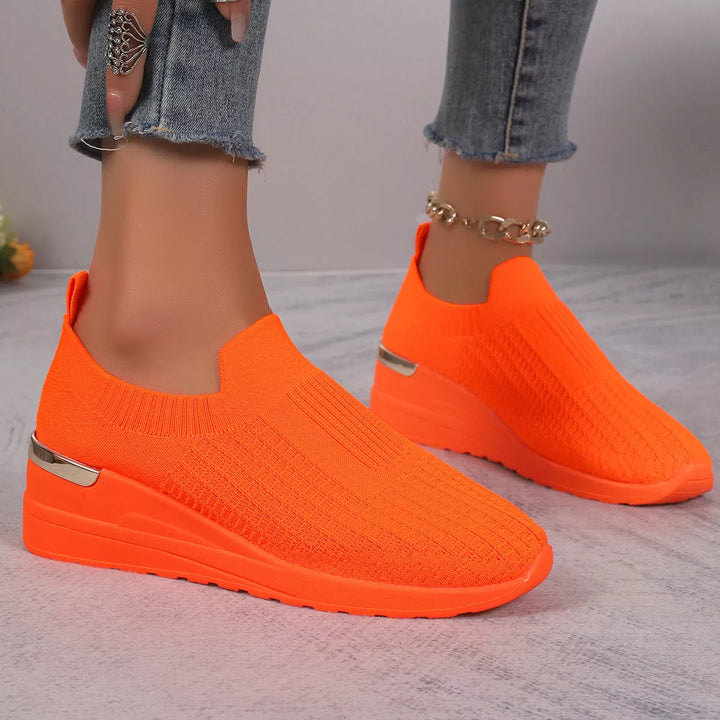 Bright orange slip on platform sneakers, pair seen from a low angle