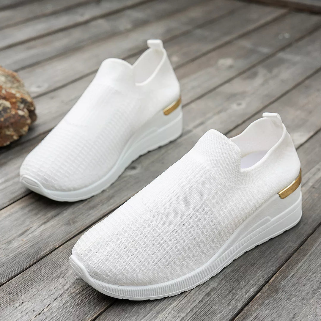White knit platform sneakers resting on a wooden floor, pair view