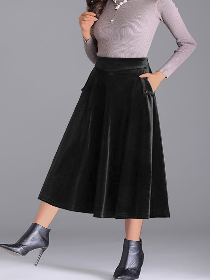 Black pleated midi skirt walking pose with pocket detail and heeled boots
