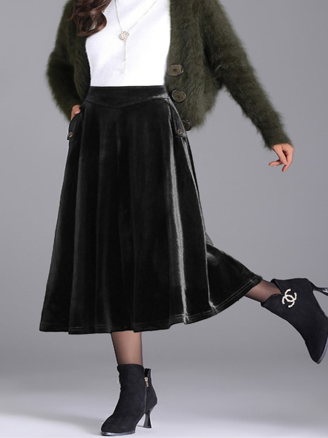 Black A line skirt with a kicked back leg, white top and fuzzy green cardigan