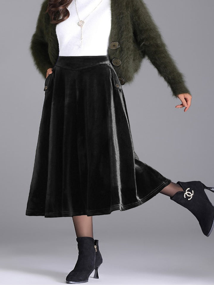 Black A line skirt with a kicked back leg, white top and fuzzy green cardigan
