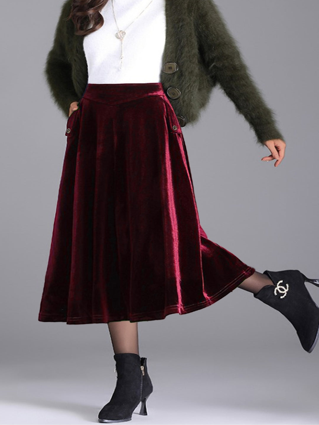 Burgundy pleated midi skirt with one boot kicked back, styled with white top