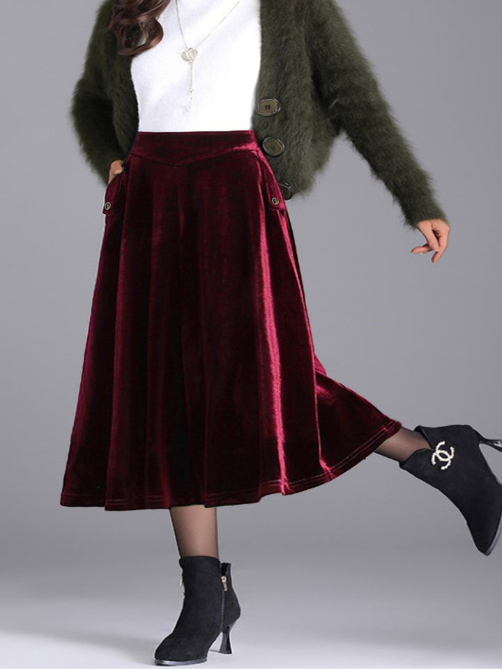 Burgundy pleated midi skirt with one boot kicked back, styled with white top