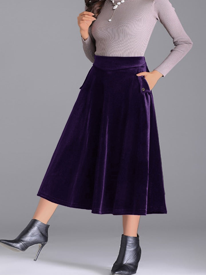 Deep purple high waist pleated skirt with hand in pocket and ankle boots