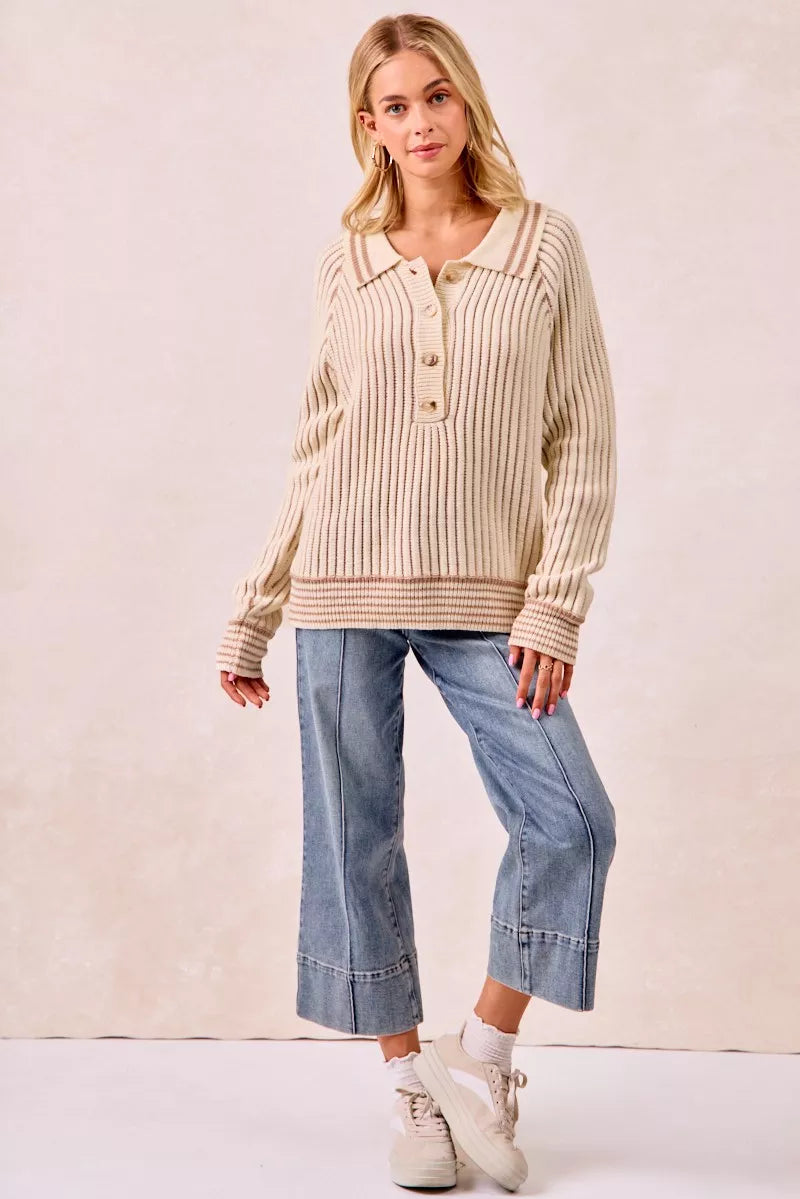 Cream ribbed polo sweater styled with cropped jeans and white sneakers, standing