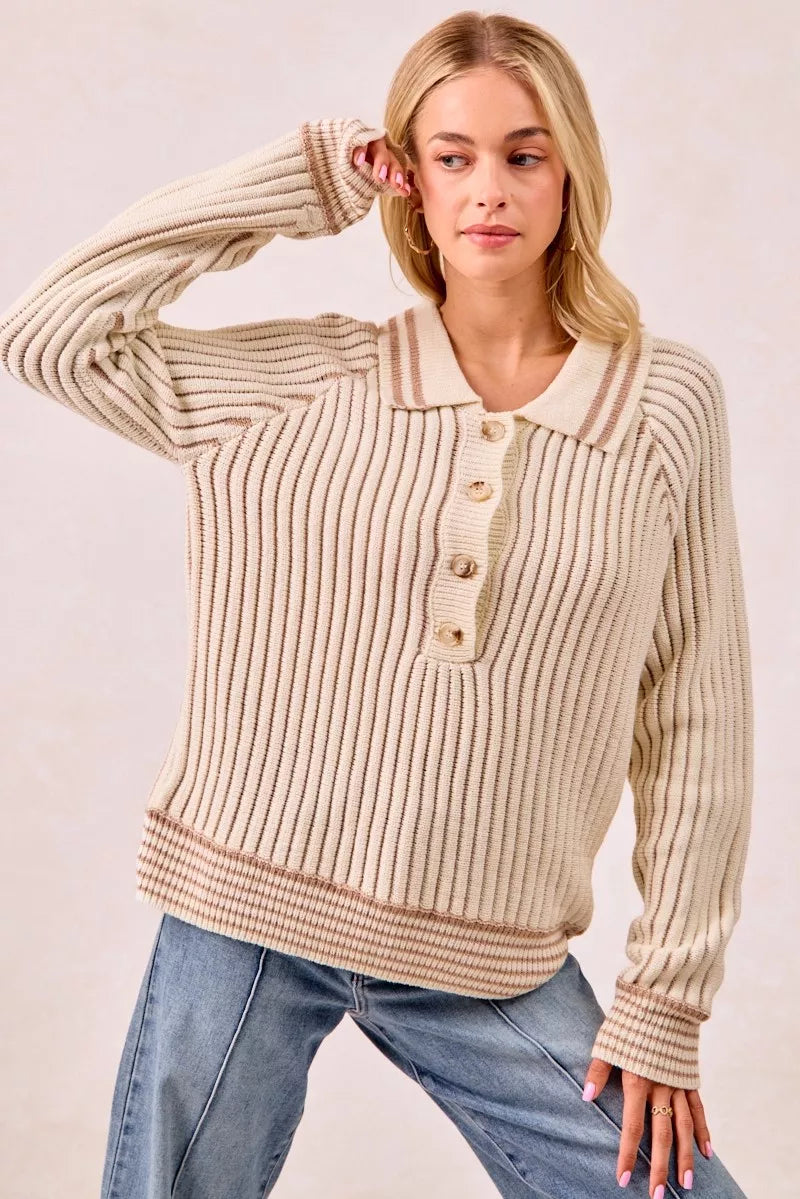 Cream half button polo sweater with a sleeve lifted above the head