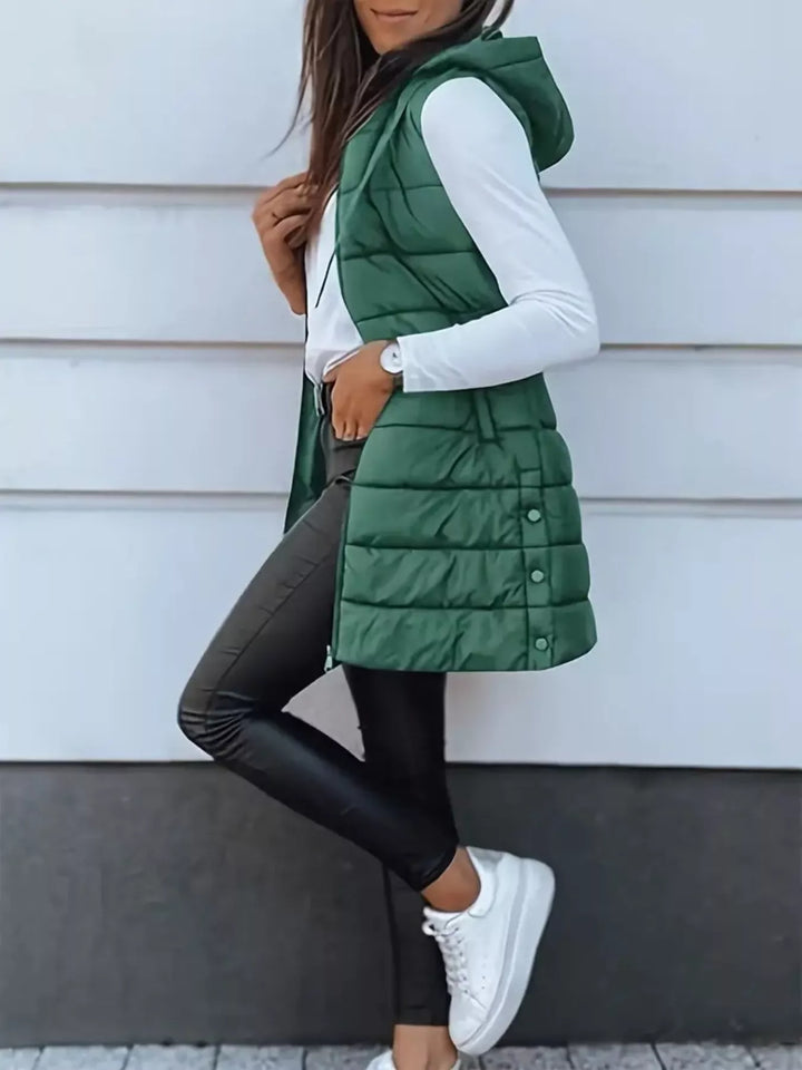 Side pose in the emerald puffer vest with black pants and white sneakers
