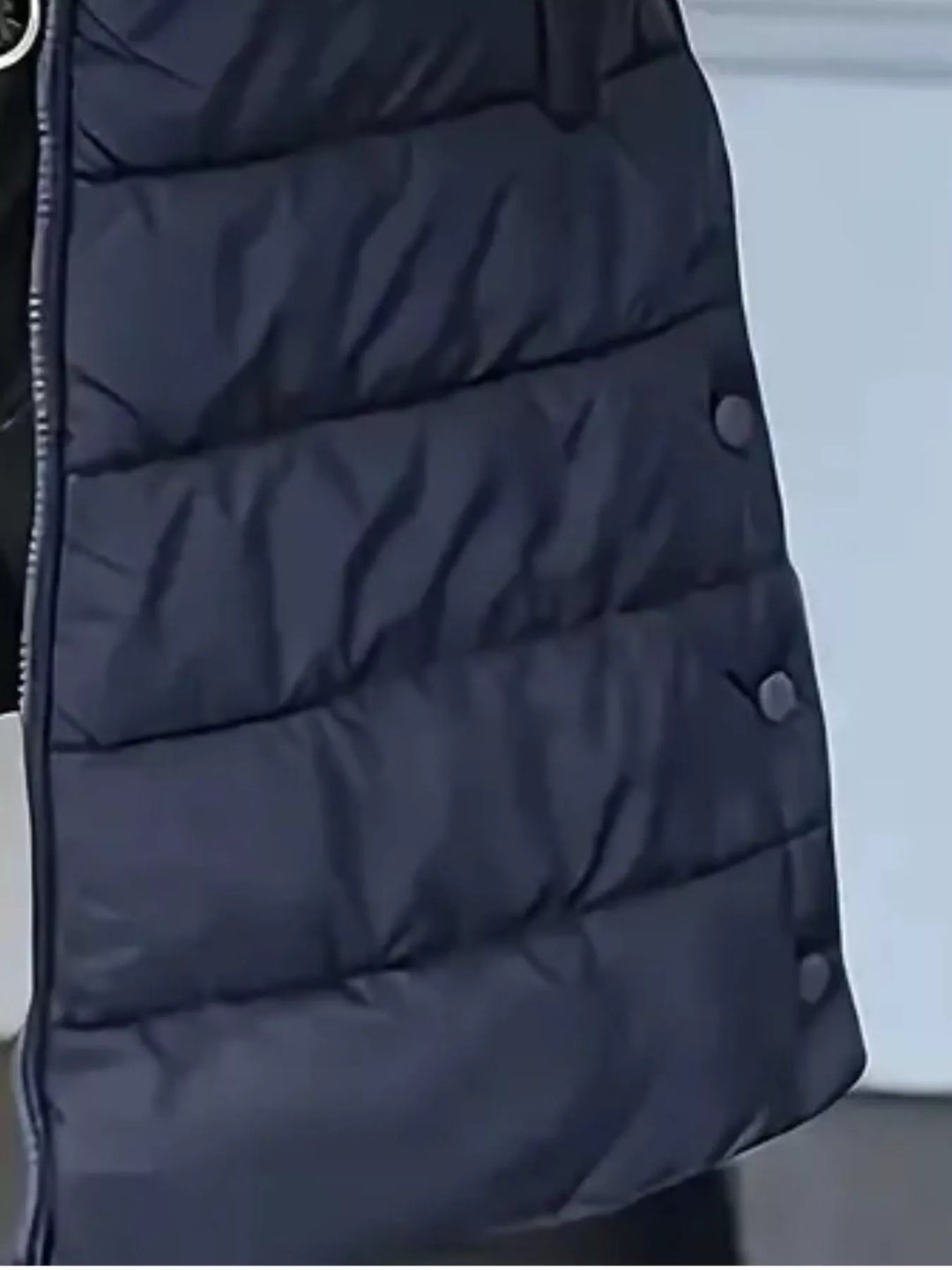 Close-up of the navy quilted vest with side snap buttons