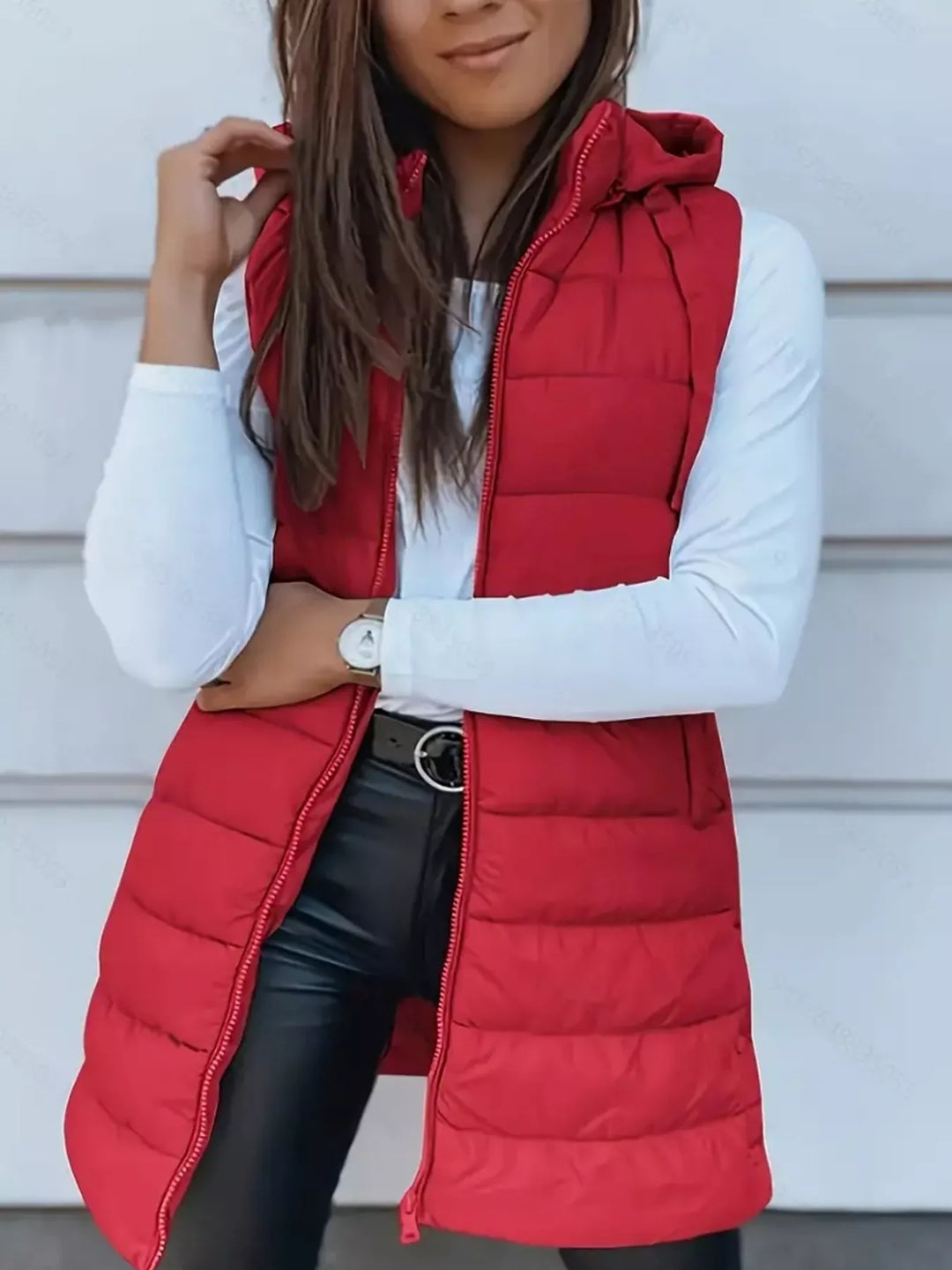 Front view of the red quilted hooded vest with hands on the hem