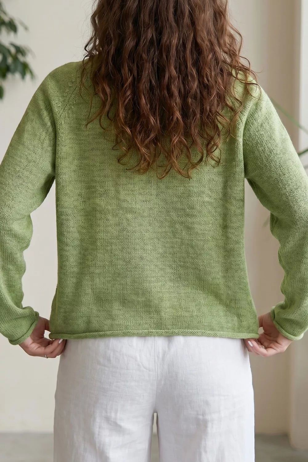 Back view of the pistachio green pullover sweater with a rolled hem
