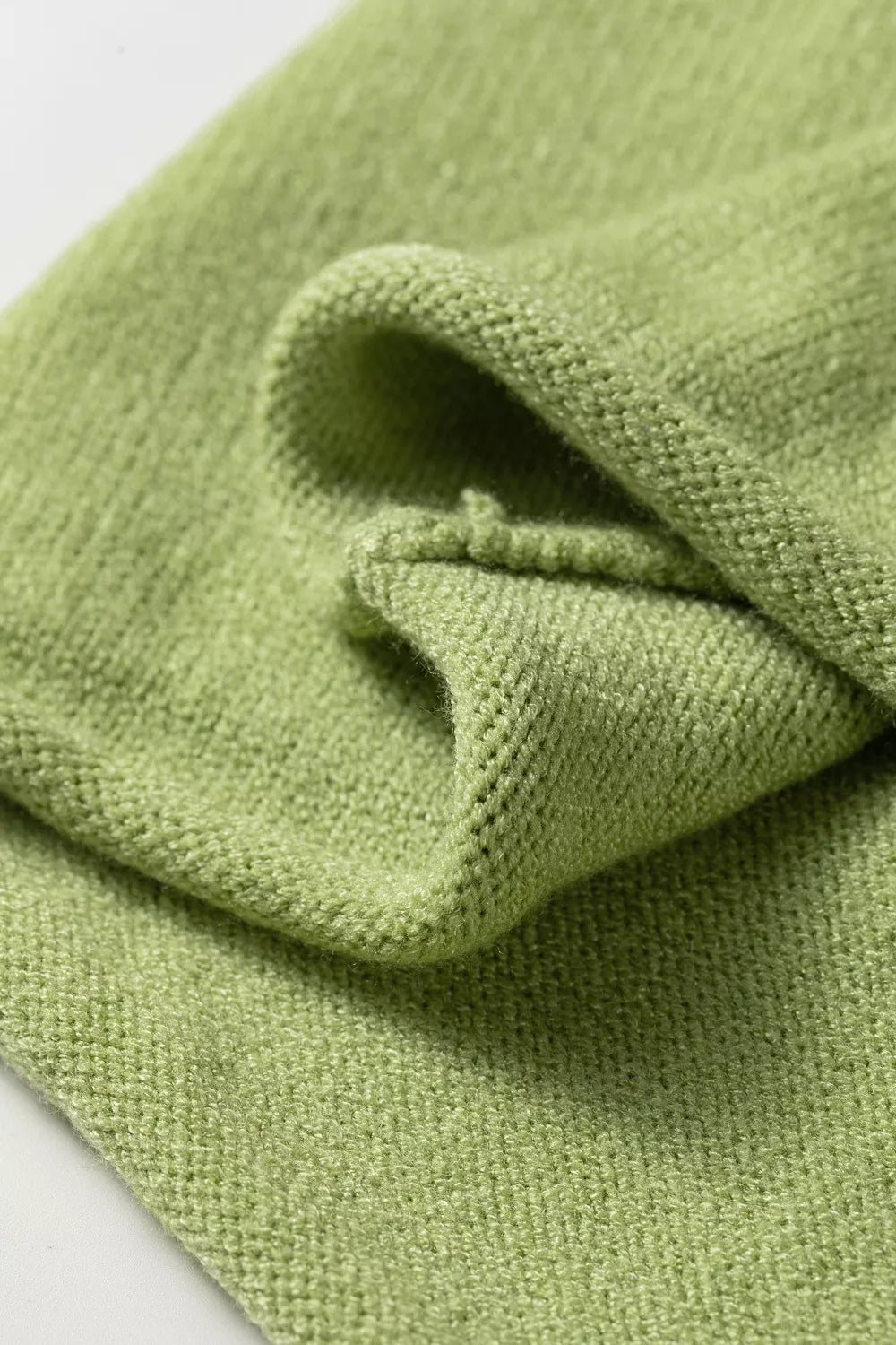 Folded detail of the pistachio green knit with a rolled hem