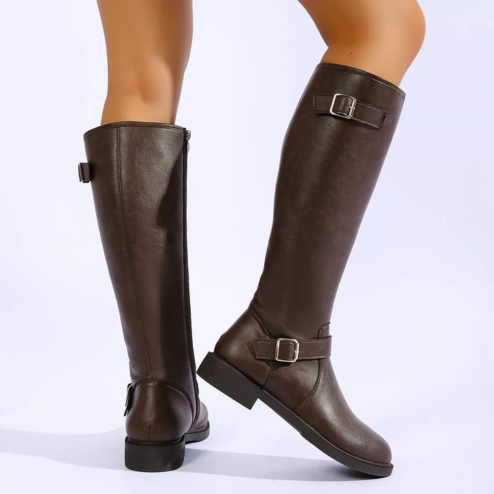 Brown riding boots with buckle straps worn mid step