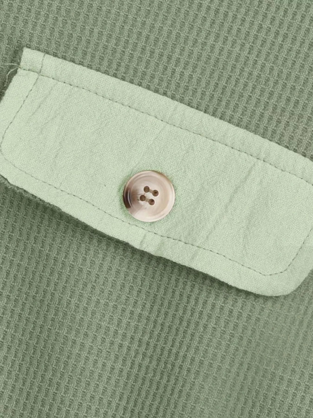 Light green waffle texture and button flap pocket up close