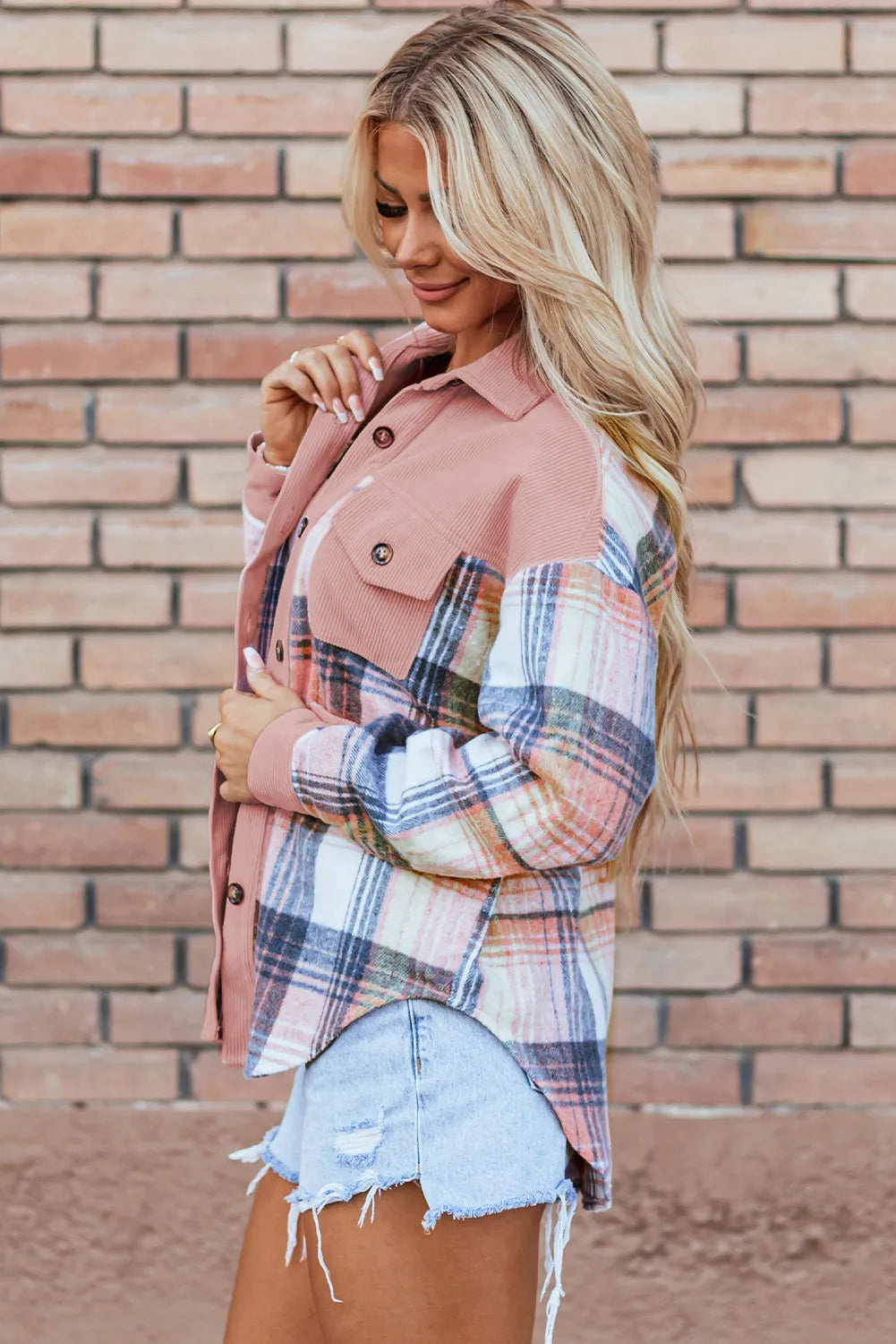Side view of the blush plaid shirt jacket against a brick wall