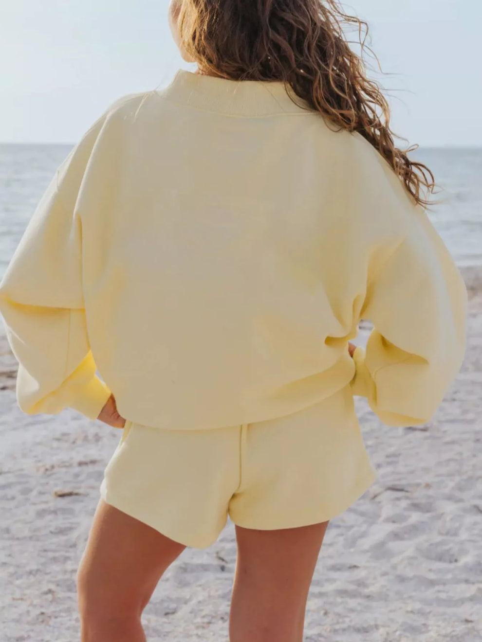 Back view of the butter yellow sweatshirt and shorts set at the shoreline