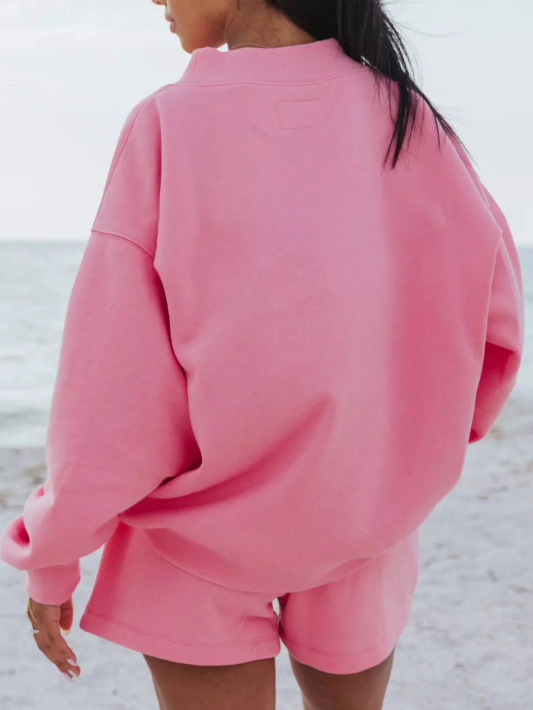 Back view of the hot pink oversized sweatshirt and shorts on the shore