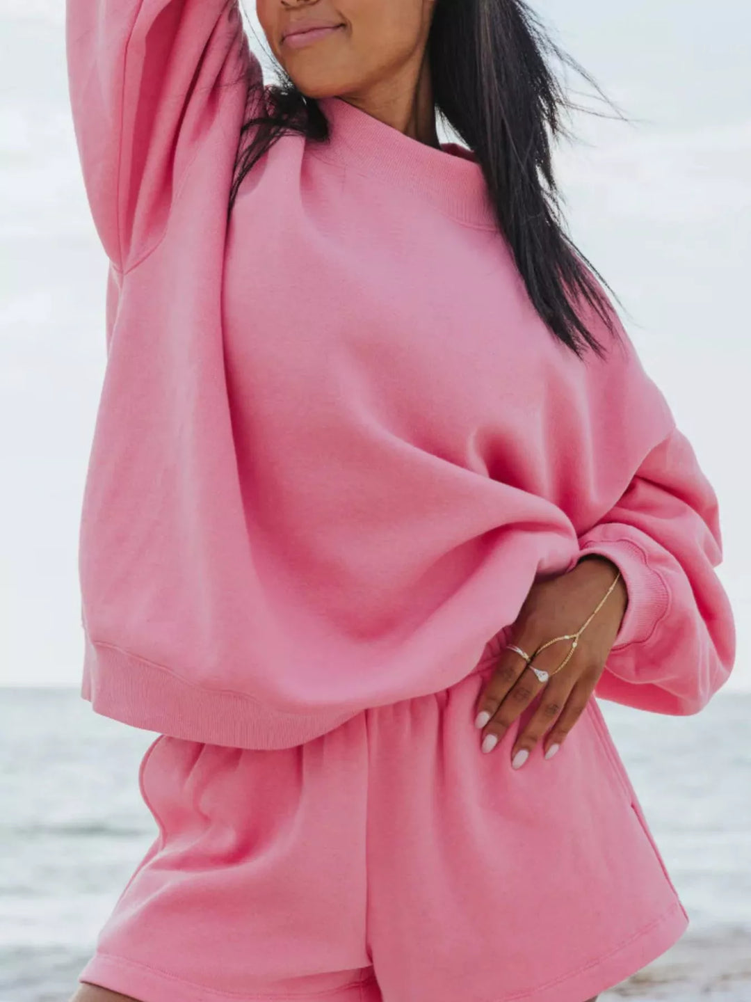 Hot pink shorts set with oversized sweatshirt, hand resting on the hem