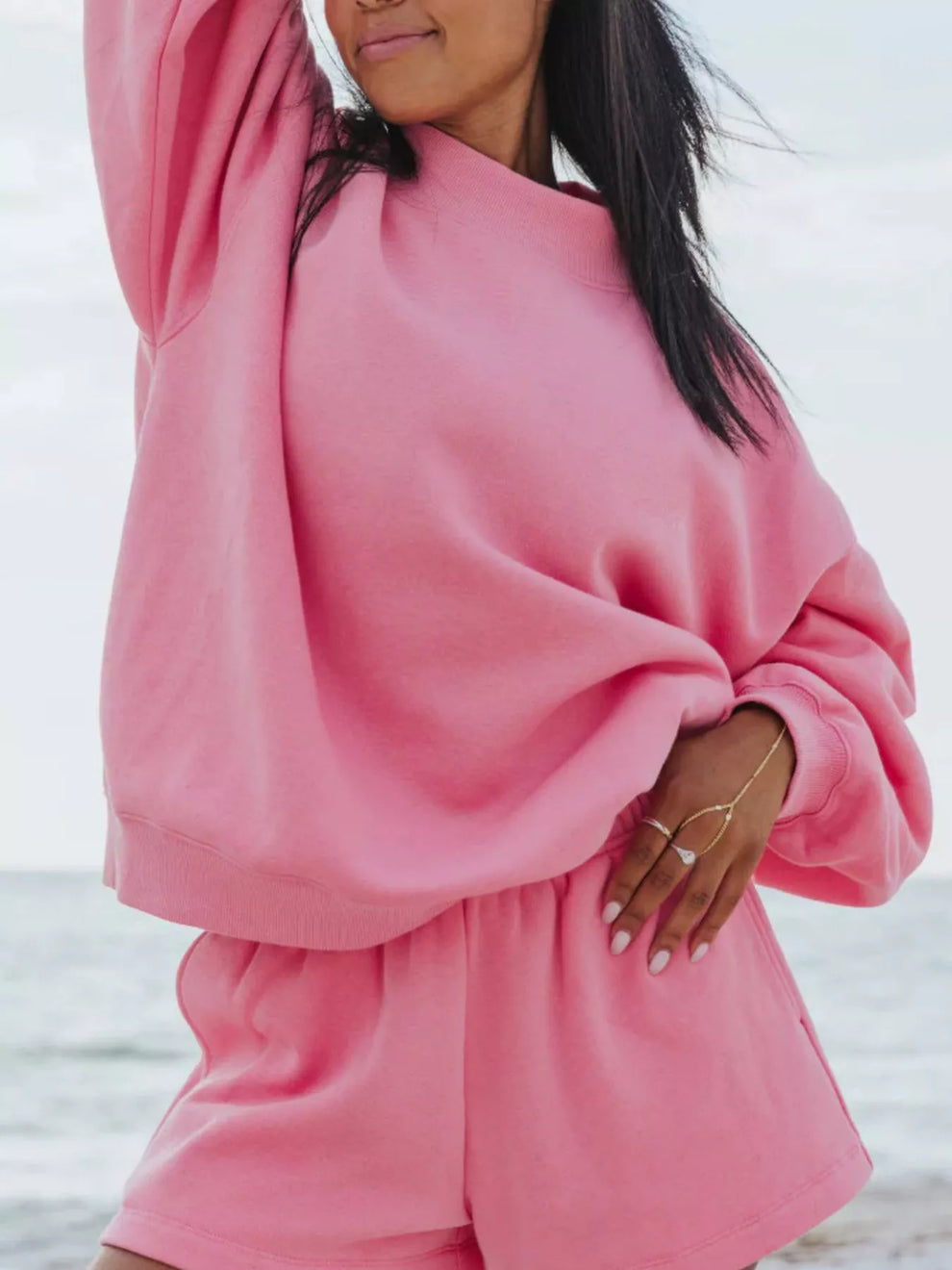 Hot pink shorts set with oversized sweatshirt, hand resting on the hem