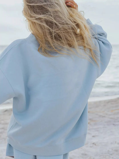 Back view of the sky blue oversized sweatshirt with long blonde hair