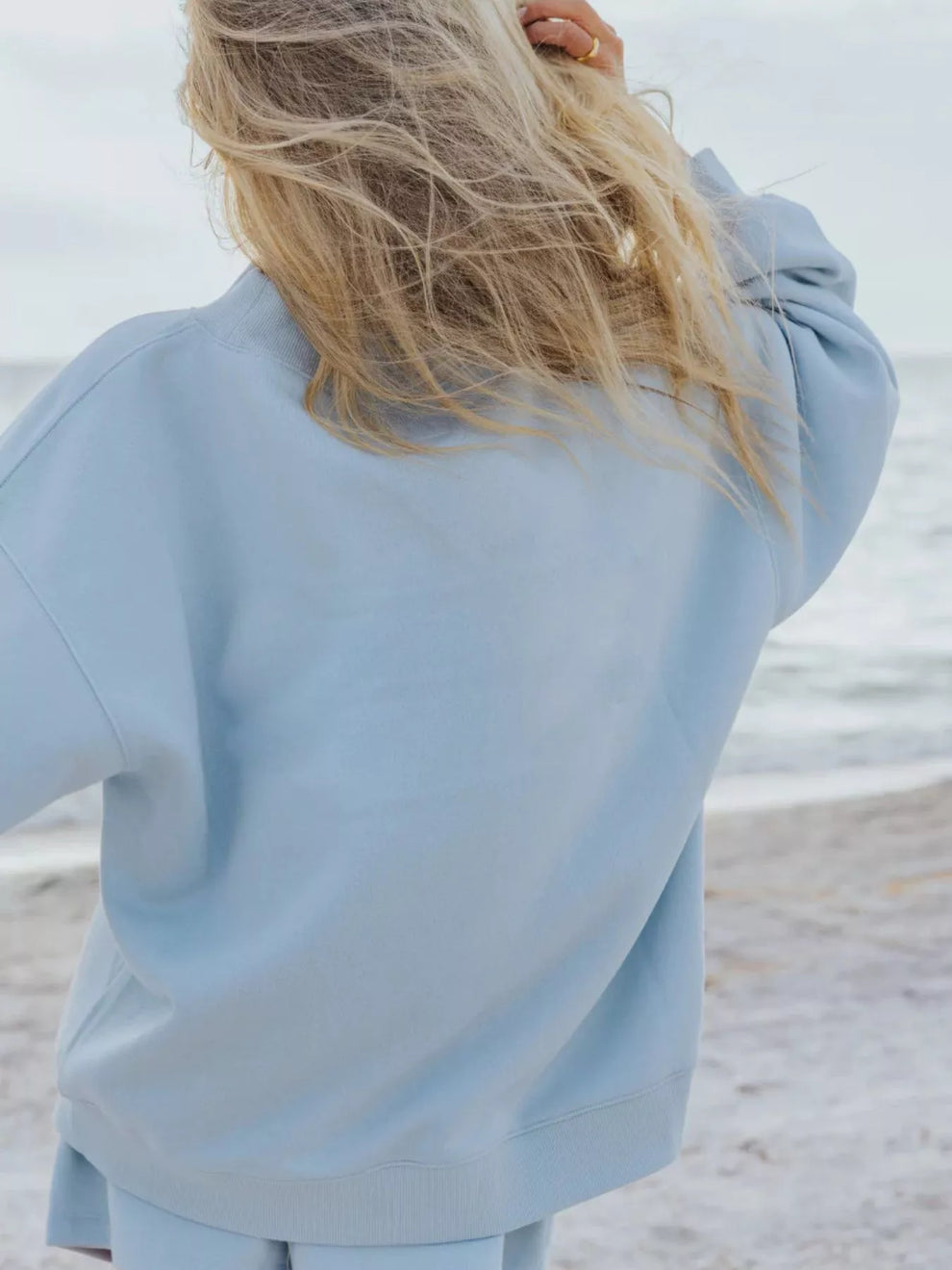 Back view of the sky blue oversized sweatshirt with long blonde hair