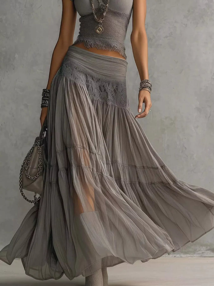 Gray tiered sheer maxi skirt flowing with a handbag, cropped from the waist down