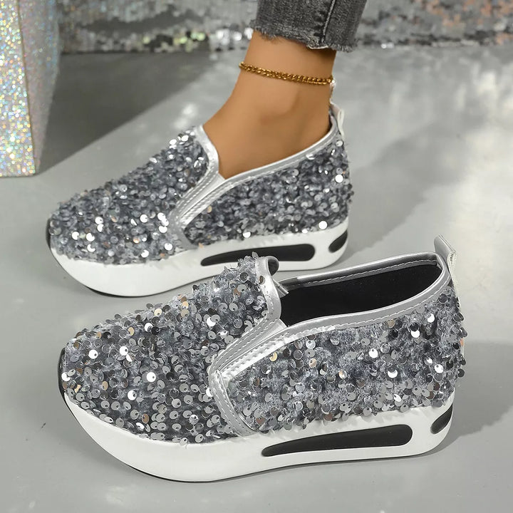 Pair of grey sequin platform slip on sneakers with silver trim, side angle