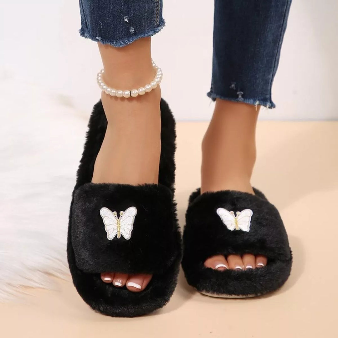 Front view of black open toe fluffy slippers worn with a pearl ankle bracelet