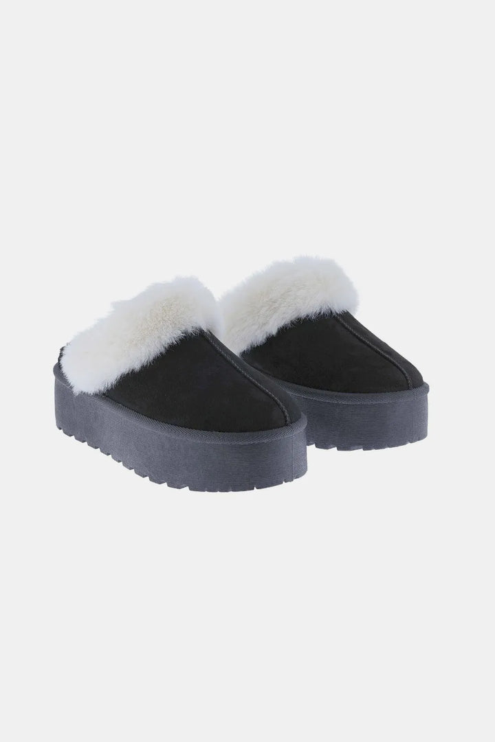 Pair of black platform clog slippers with plush white trim, angled view
