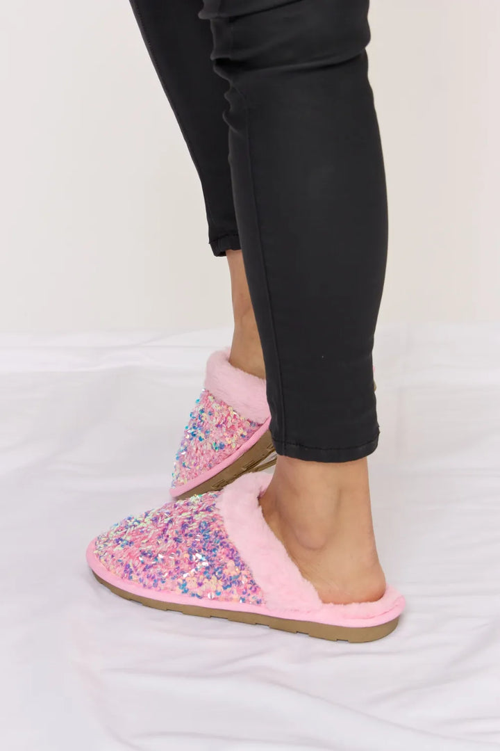 Side profile of a pink sequin slipper with plush collar