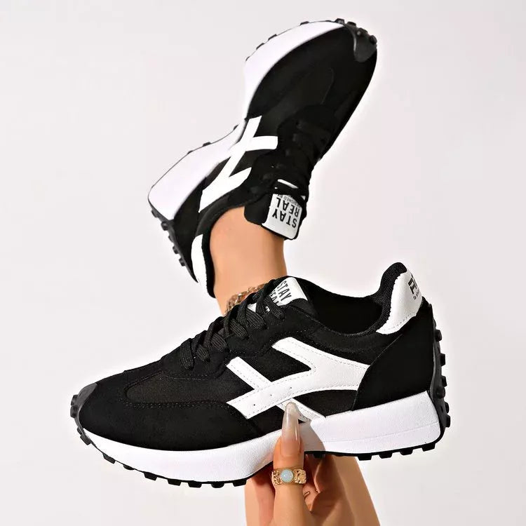 Black platform sneakers with mesh panels held up to show the side profile