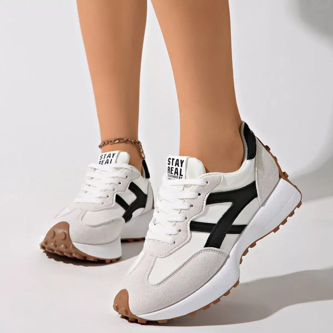 Light gray chunky platform sneakers with black accent, worn with an ankle bracelet