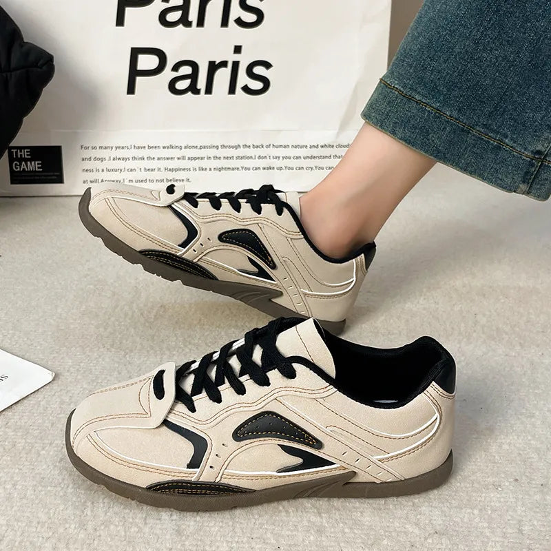 Cream and black lace up sneakers worn with jeans next to a paris shopping bag