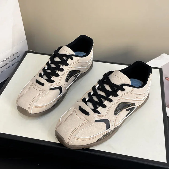Pair of cream black retro sneakers with black laces on a white display box