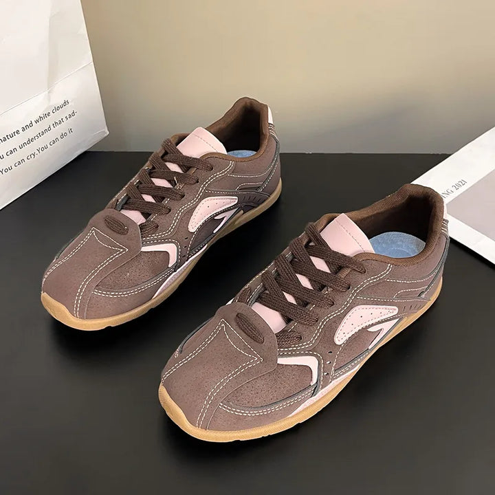 Pair of mocha pink retro lace up sneakers with contrast panels on a dark surface