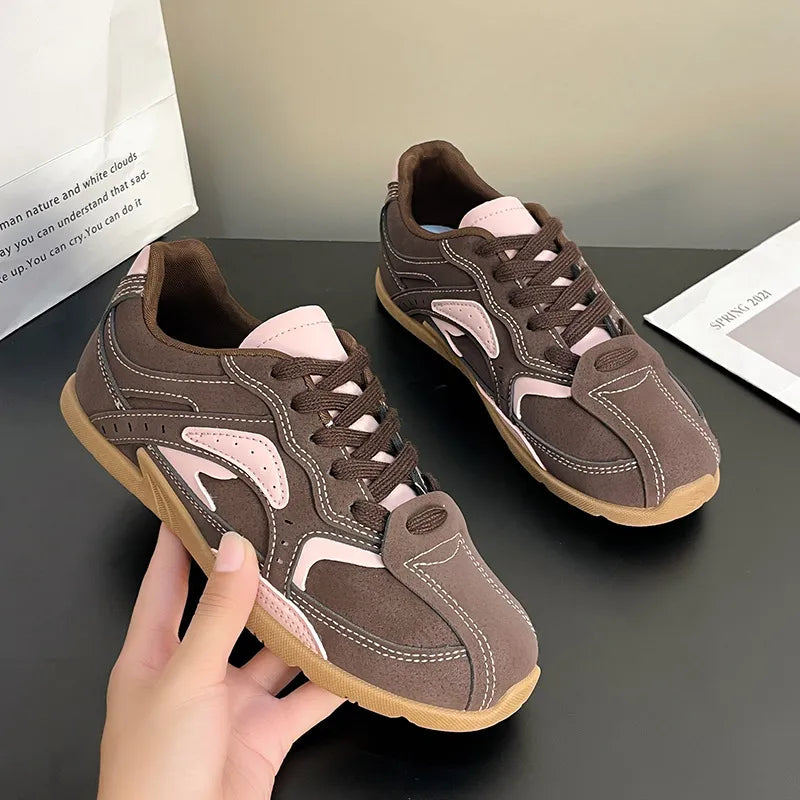 Hand holding a mocha pink retro sneaker to show the gum sole and panels