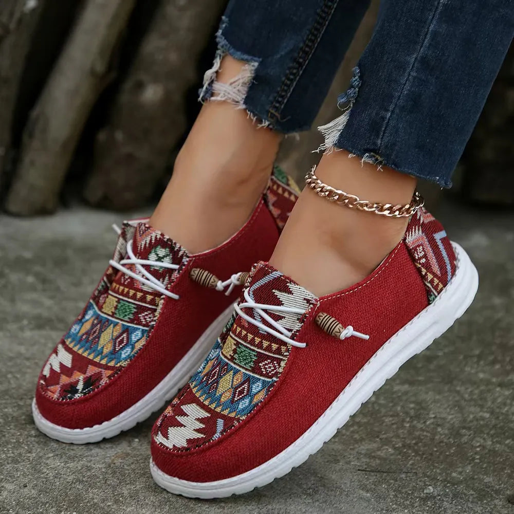 Deep red Aztec print slip on sneakers with white laces, worn with ripped jeans